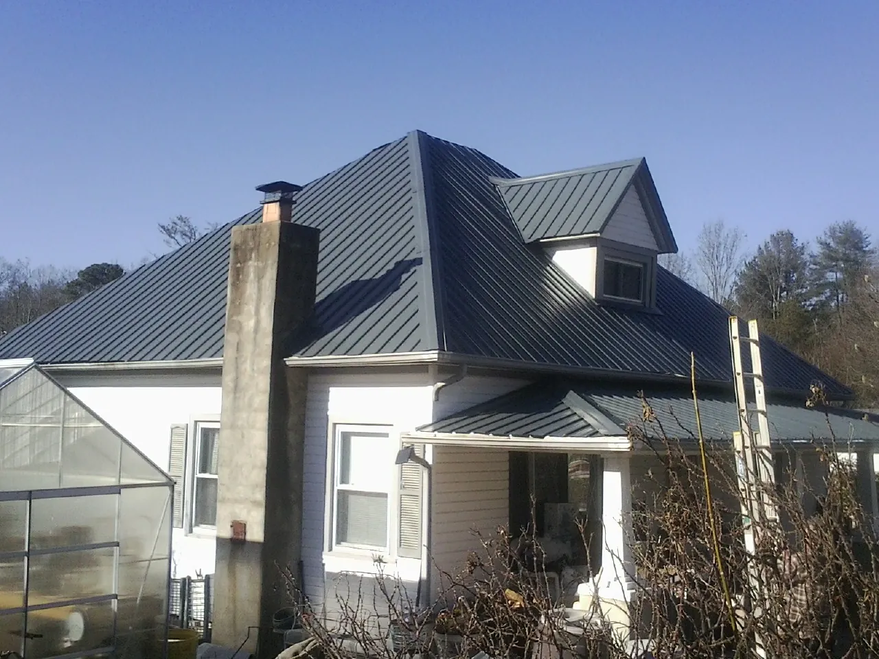Dark blue standing seam metal roof on a white farmhouse with dormer — Slate & Tile Roof Repair by Roofing Brothers in Valley Lee