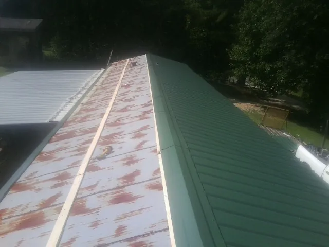 Old rusted panels beside newly installed green metal roofing — Wind Damage Roof Repair by Roofing Brothers in Valley Lee