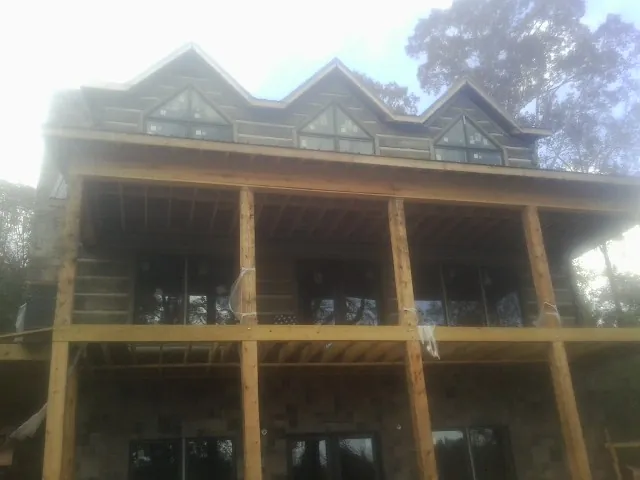 Dormers and porch framing on a large log home under construction — Roof Coating work by our crew in Valley Lee