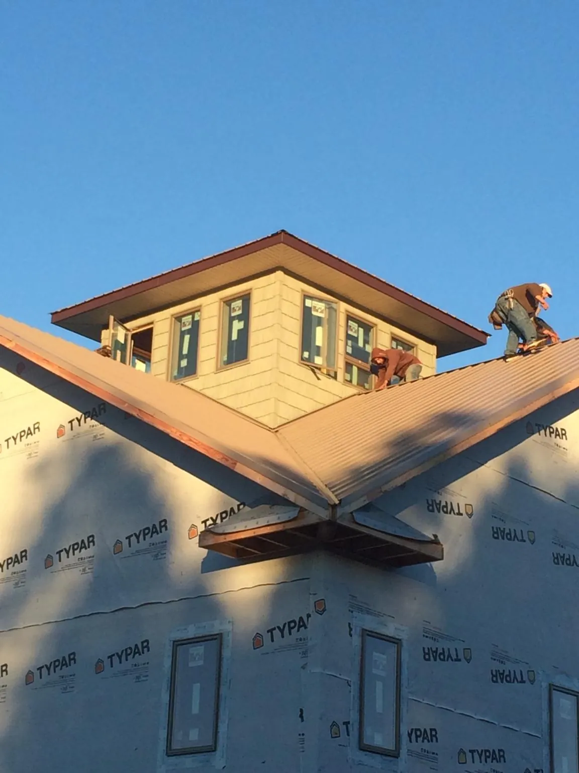 Roofers working around a rooftop cupola on a new metal roof at sunset — Roof Waterproofing in Valley Lee by Roofing Brothers
